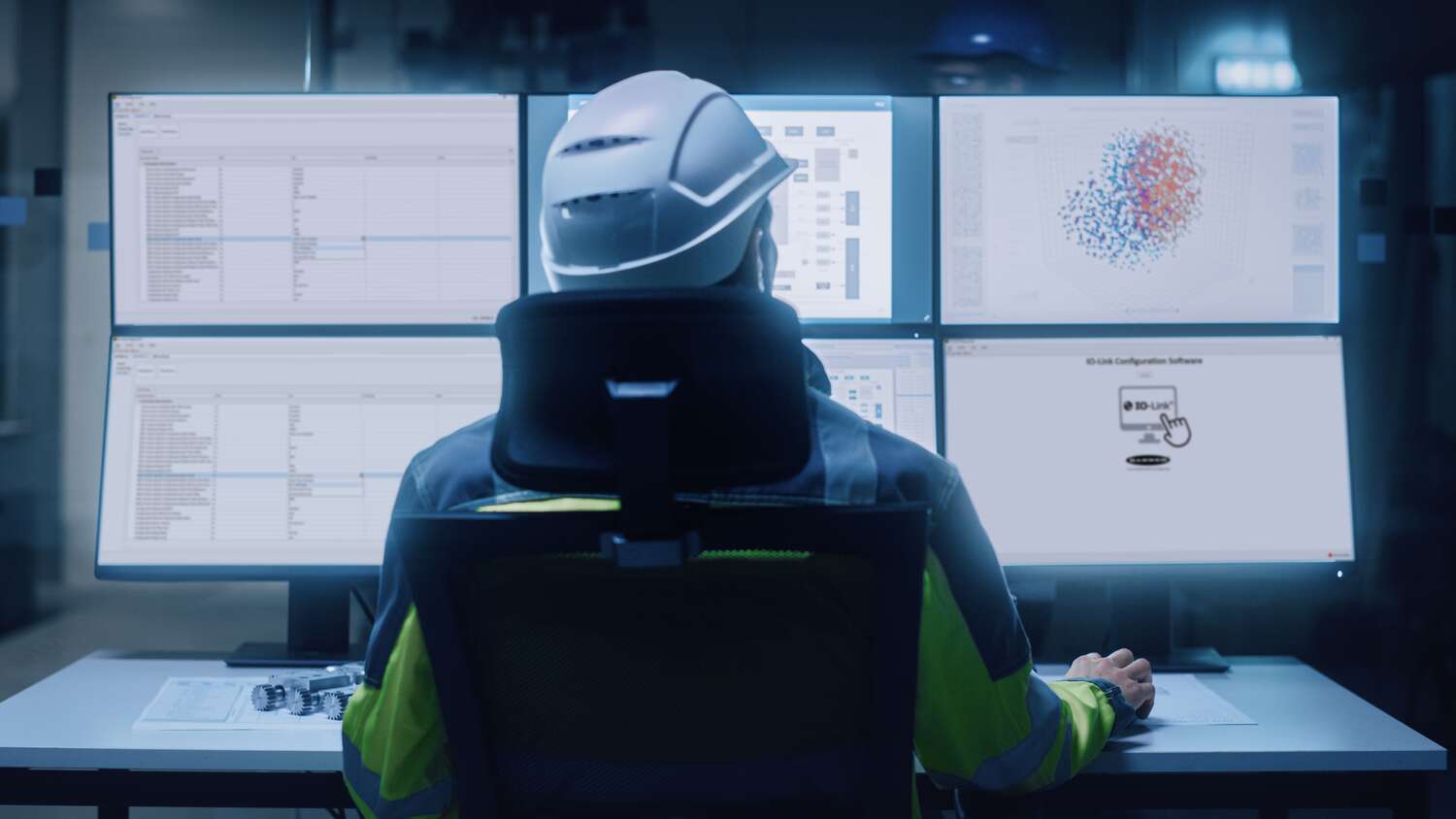 Engineer sits at a table with multiple computer screens